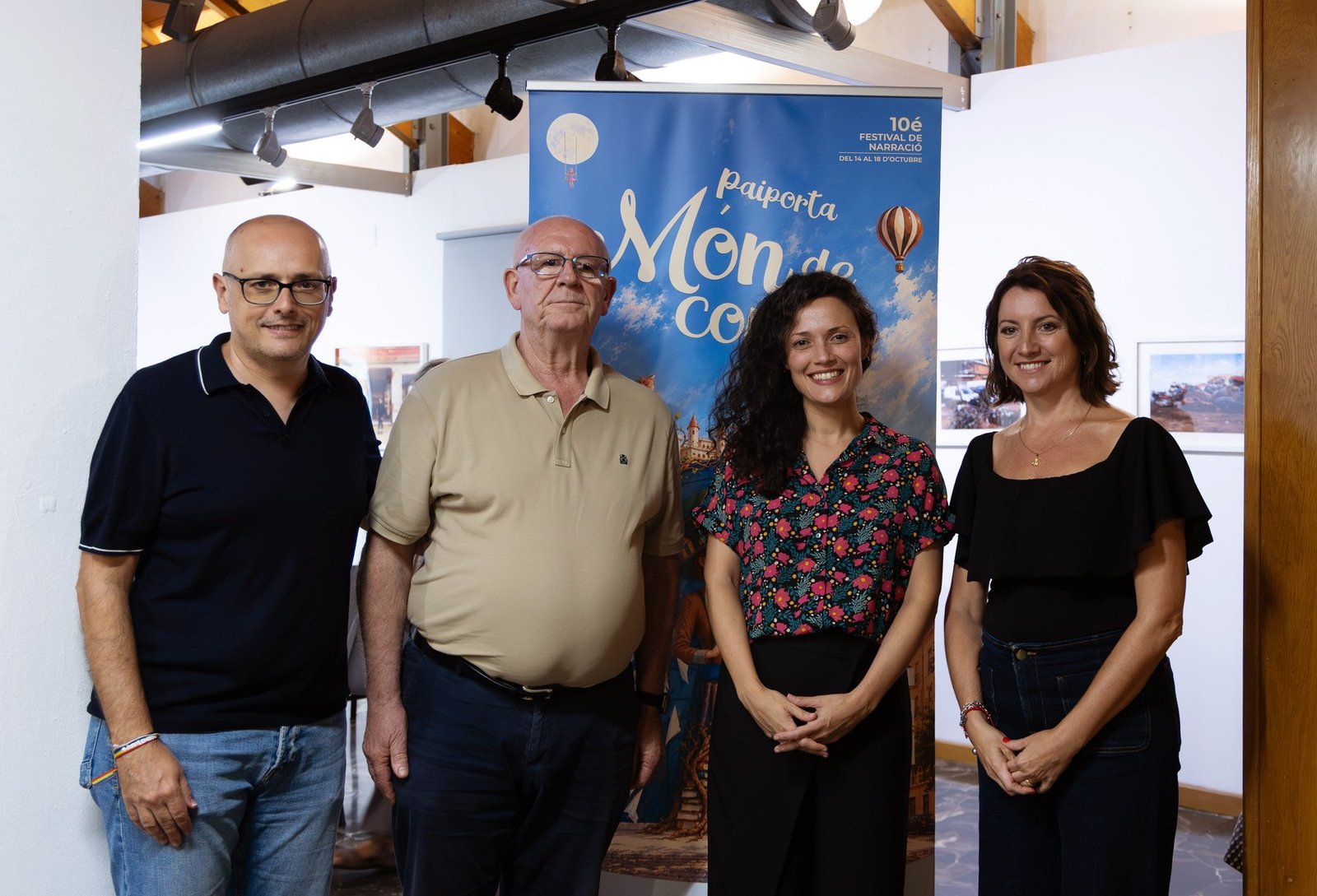 Cuatro personas posan junto al cartel del 10.º Festival de Narración Oral Paiporta Món de Contes en el Museu de la Rajoleria